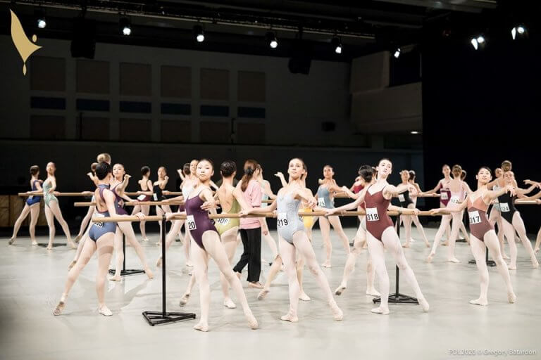 Young ballerinas warming up at the barre during the competition